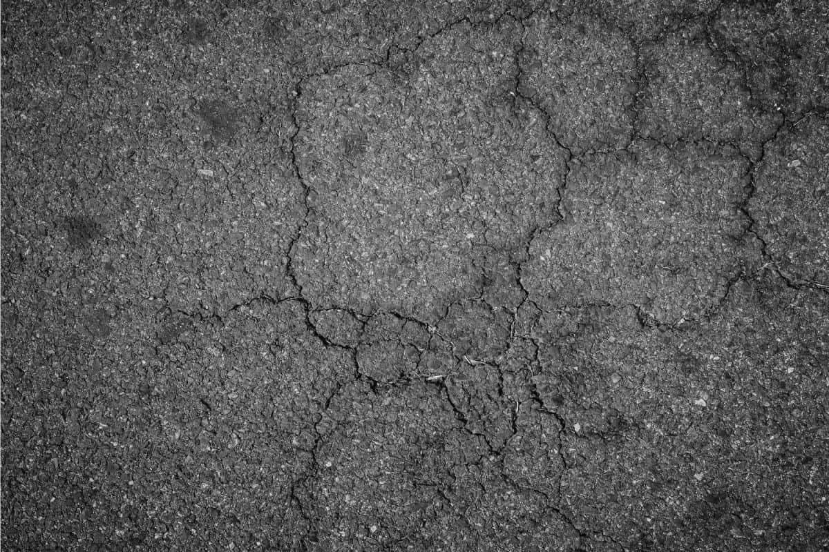 Full frame grunge background of cracked old asphalt pavement