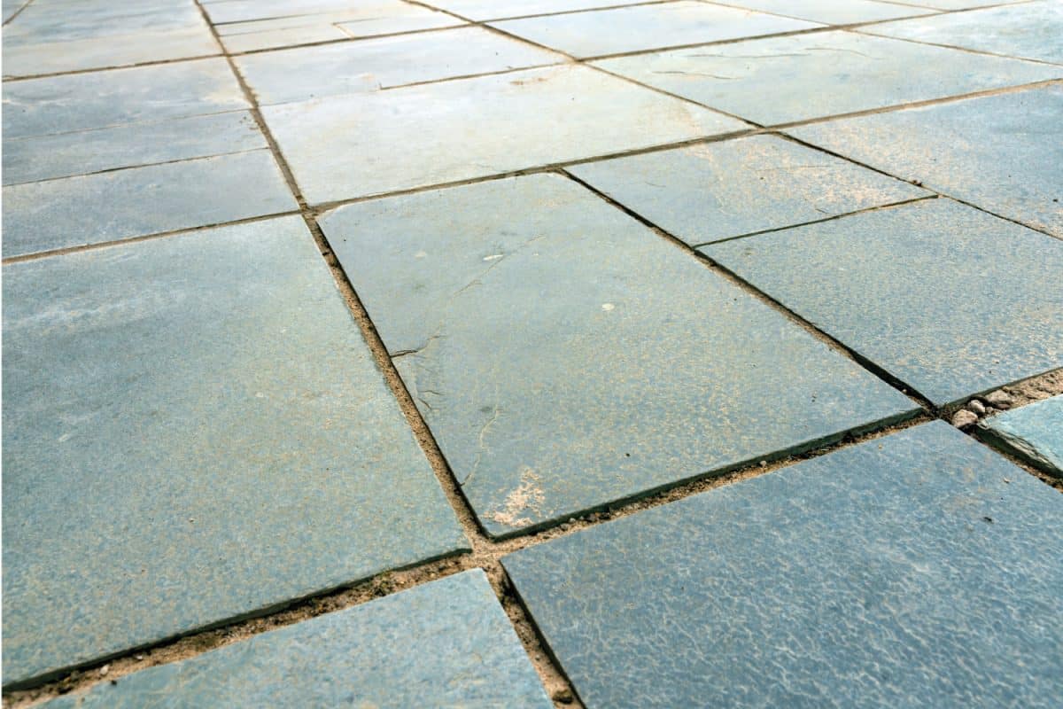 Green slate patio before re-grouting with gaps between slate slabs
