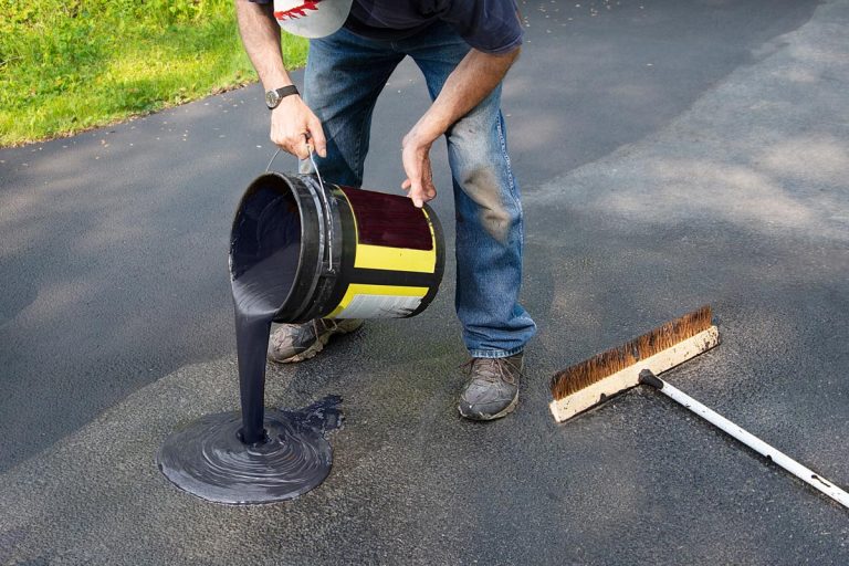 A homeowner pours blacktop sealant onto driveway, Does Asphalt Seal Coating Work? [Is It Important?]