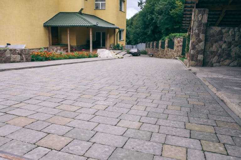 Nested pavers of various colors, around the grass is green, chic garden, How Long Before You Can Drive On Pavers?