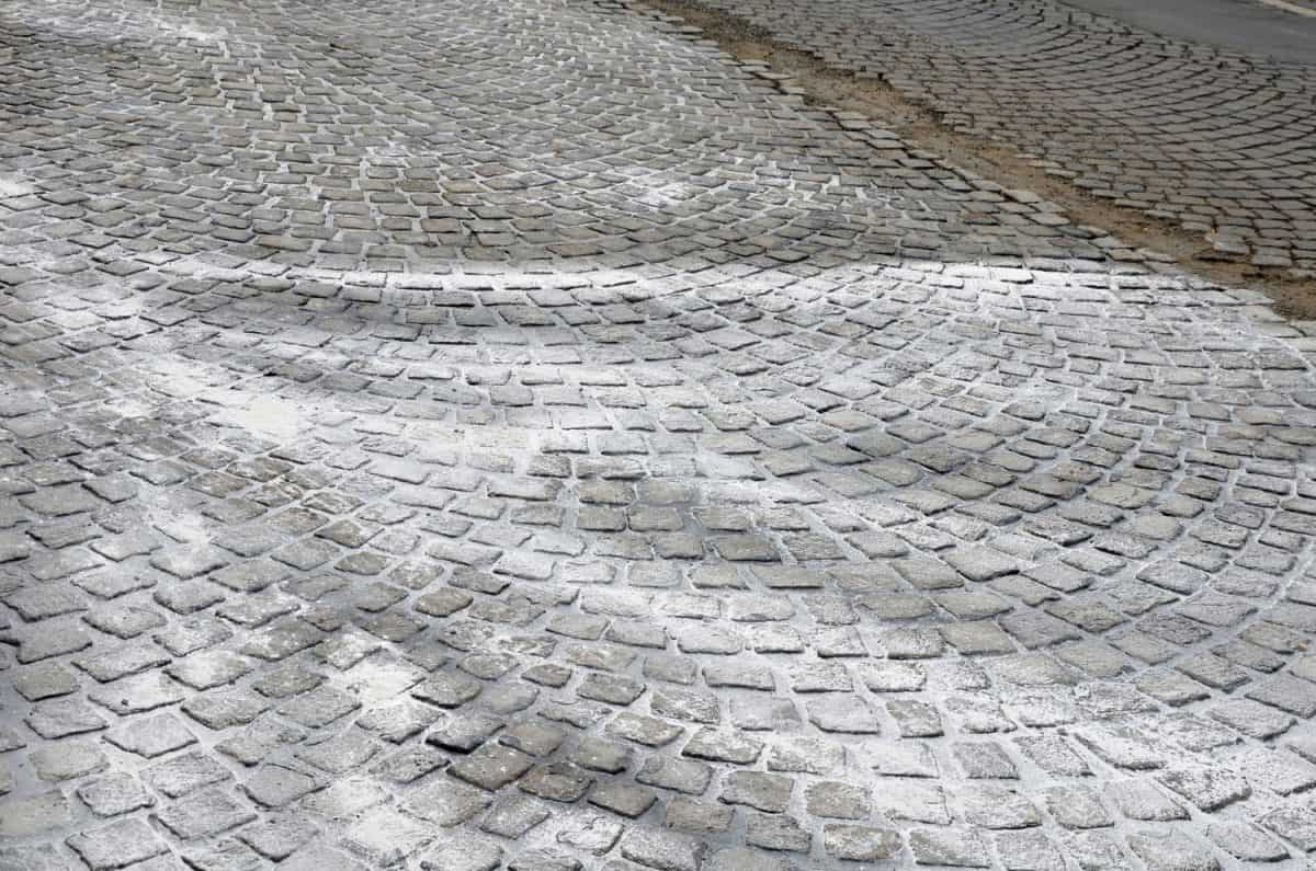 repair of cobblestone road. between the joints of the cube is poured asphalt which is sprinkled from the top with fine white silica sand so that it does not stick to the wheels of the car