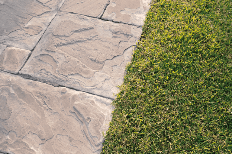 Sidewalk with grass on the side. Is Flagstone Slippery When Wet [What You Should Know About Flagstone Hardscapes]
