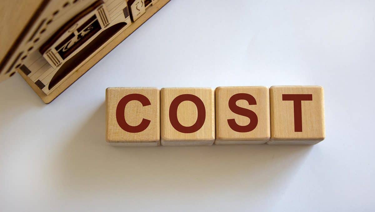 Wooden cubes form the word 'cost' near miniature house