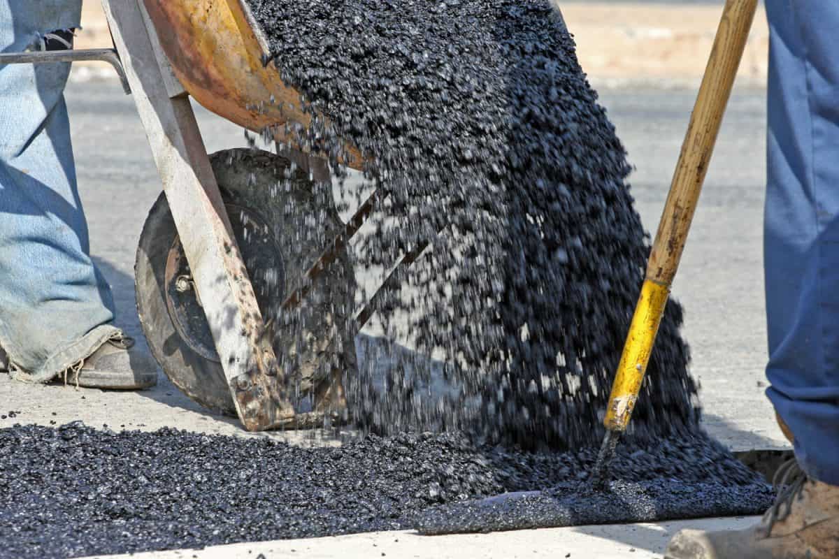 Worker laying out asphalt for road rehabillitation