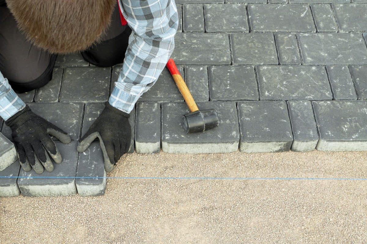 Worker properly placing concrete pavers on the patio flooring