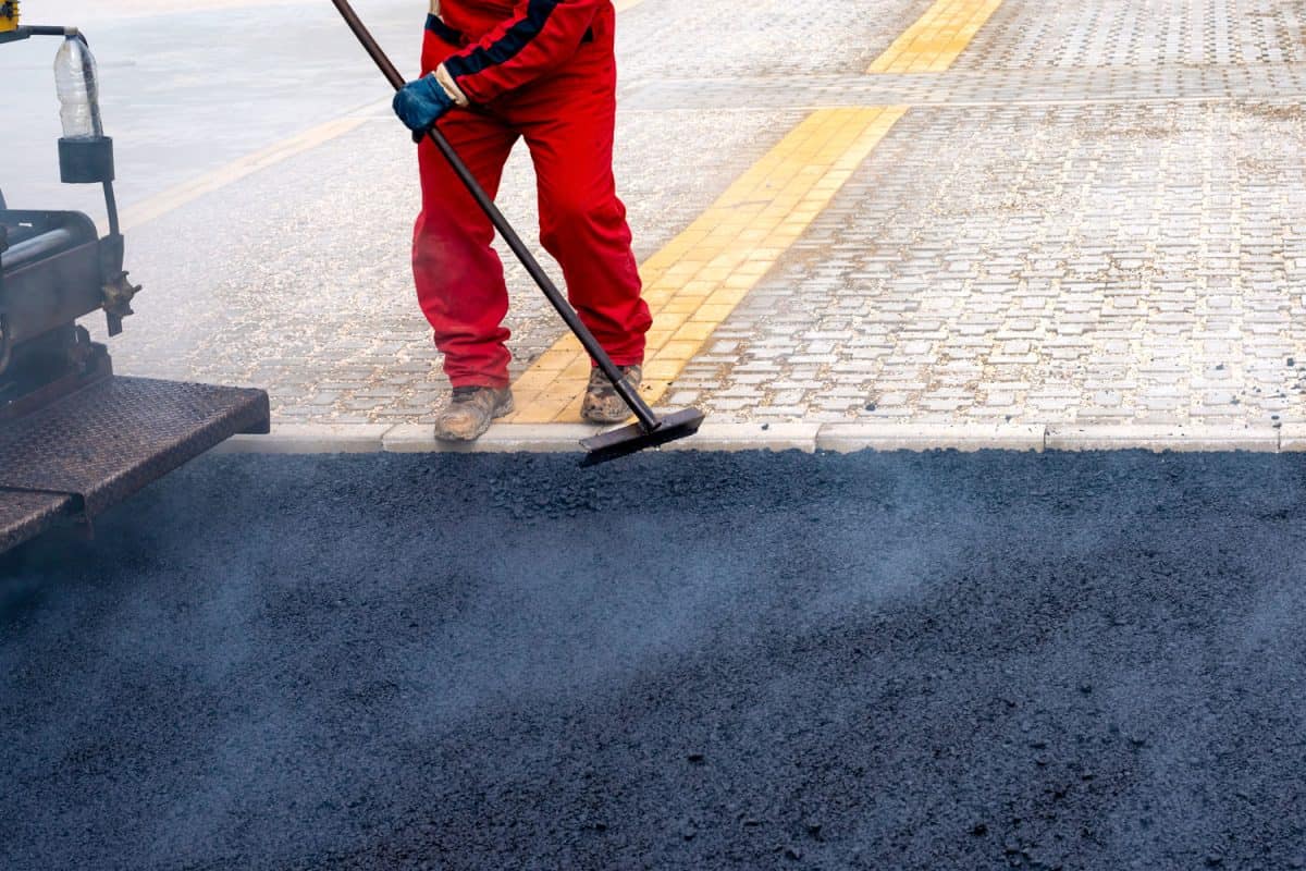 Worker sweeping asphalt on the road