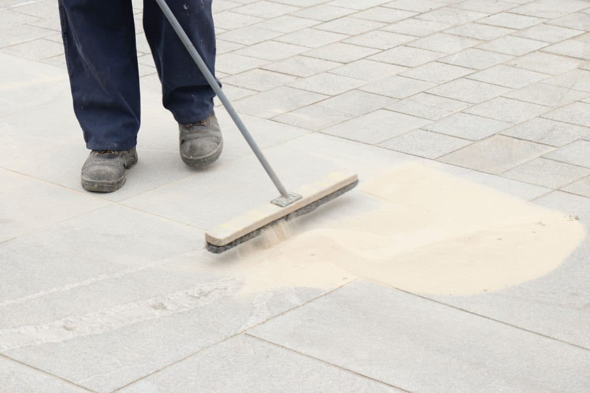 Worker sweeping sand on the pavement