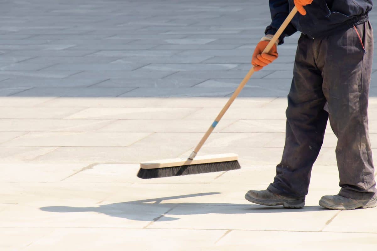 Worker sweeping the polymeric sand on the construction site