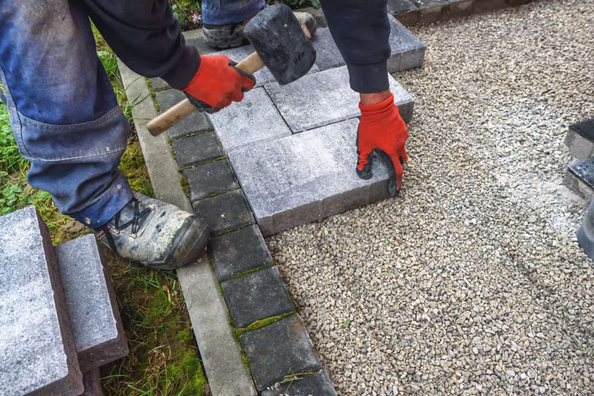 Worker using a mallet to layout the six inch brick for the patio pavement