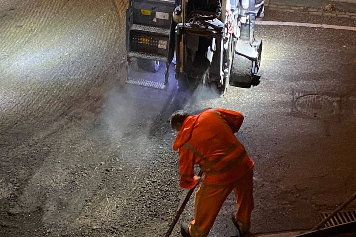 Worker using a rake for the road
