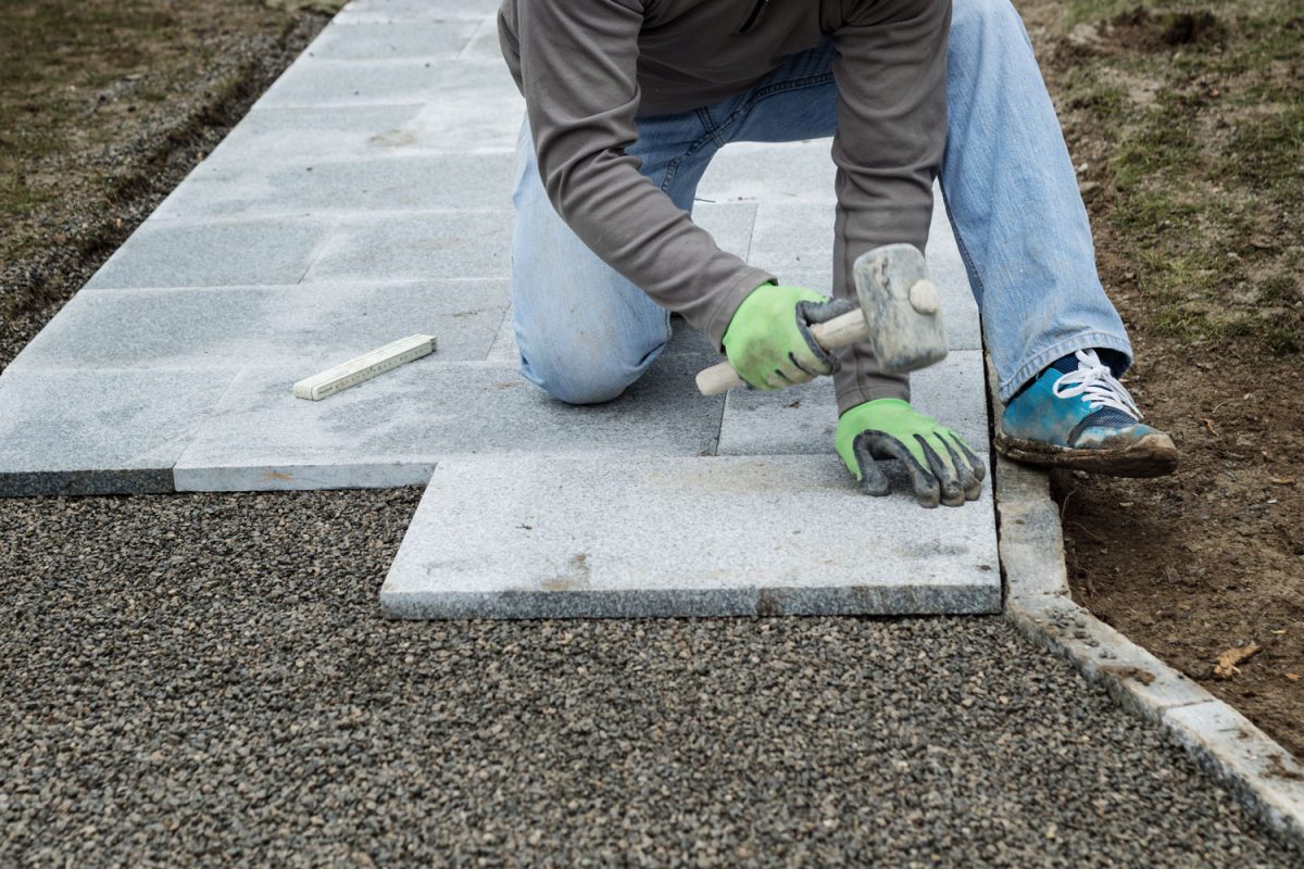 Worker using a rubber mallet for laying out concrete pavers
