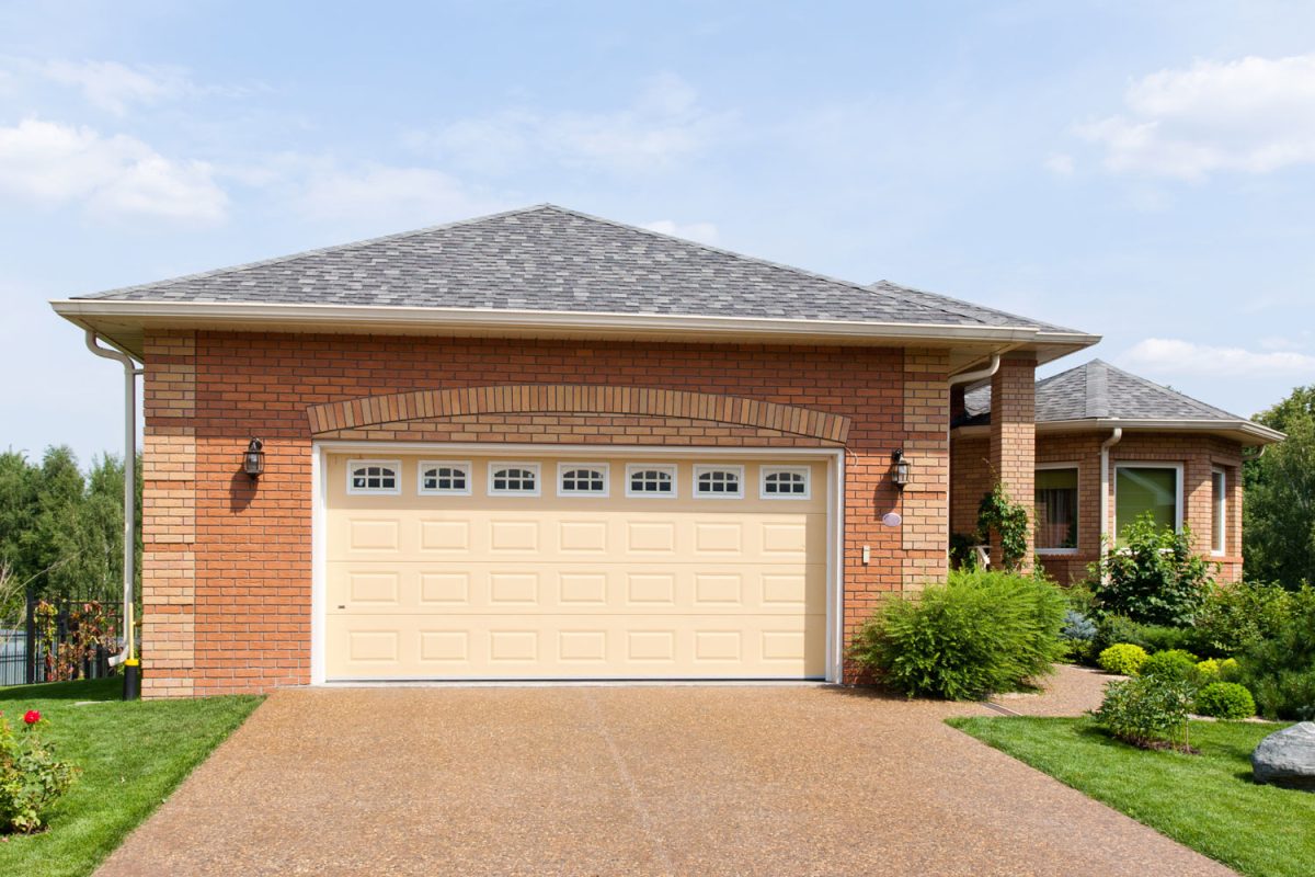 A driveway with pebble driveway matching the color of the garage door