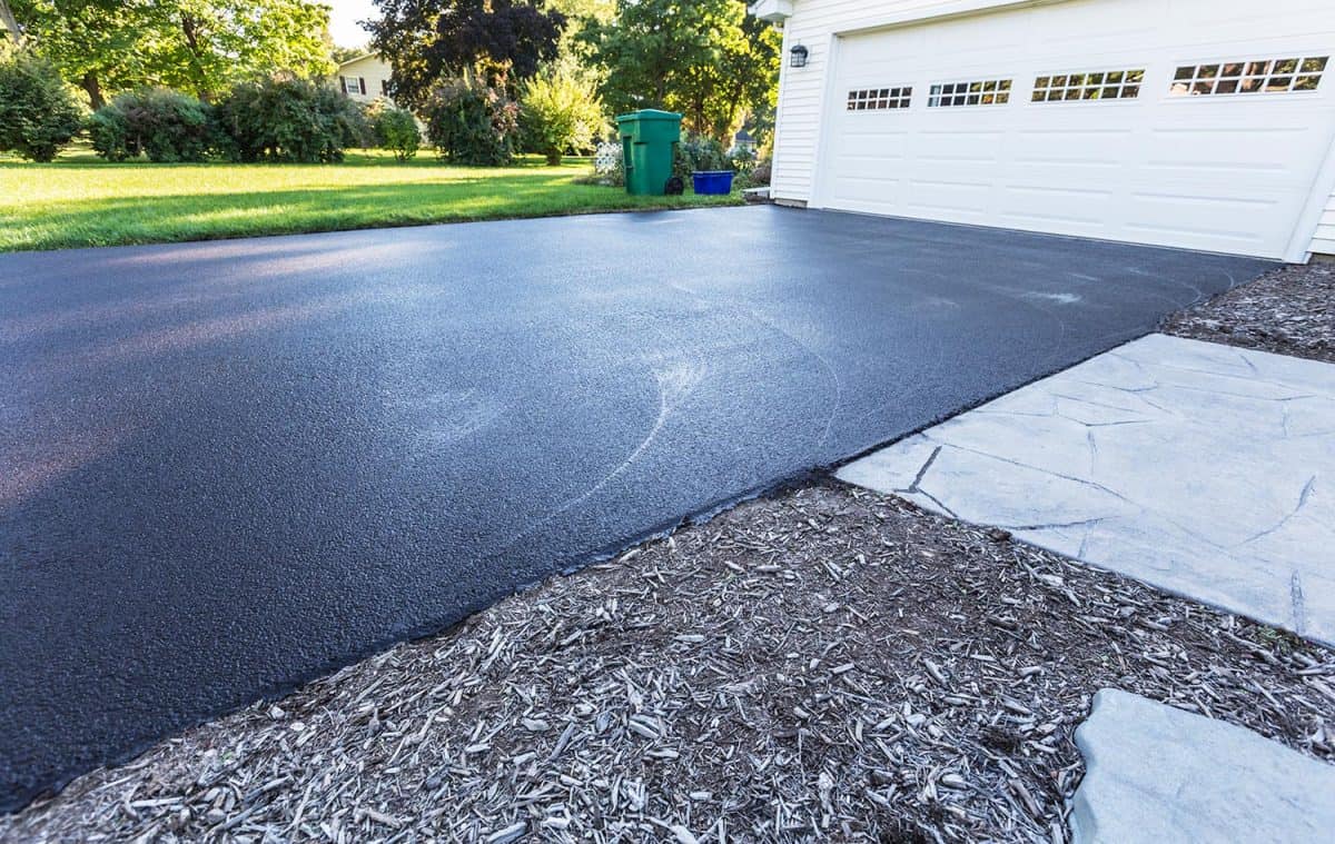 A fresh blacktop resealing job just finished on this asphalt driveway in a suburban residential district