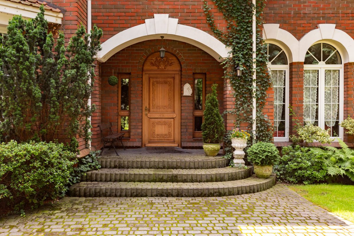 A huge brick house with a hardwood door and an arched entryway