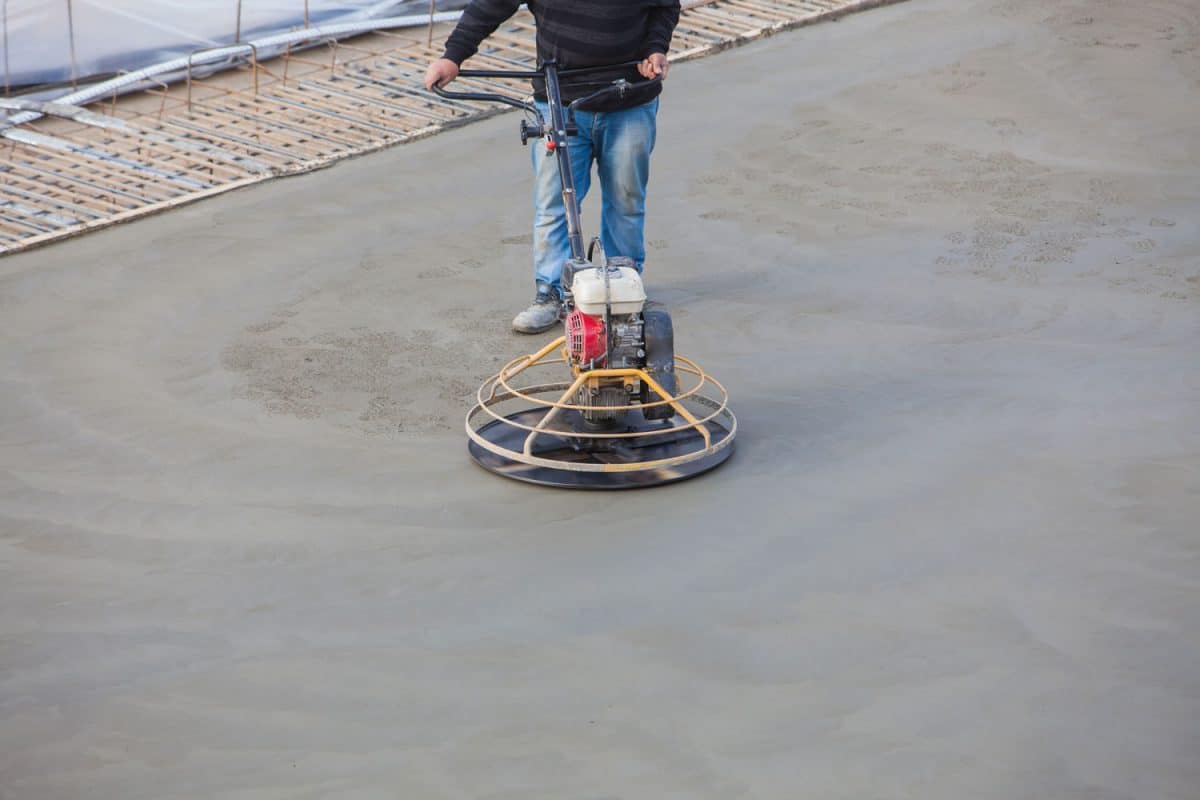 A mason using concrete polisher for the house flooring