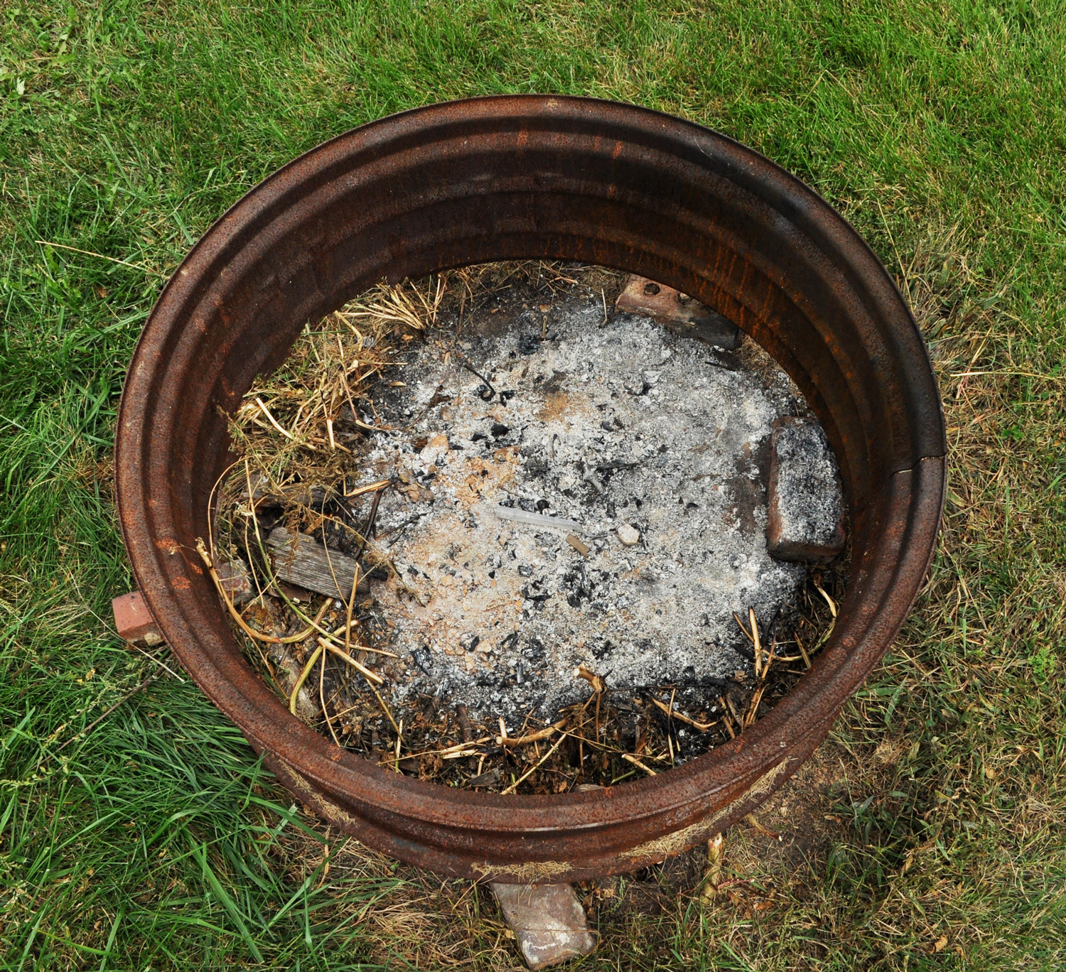 An outdoor fire pit with ashes in it within a metal hub.