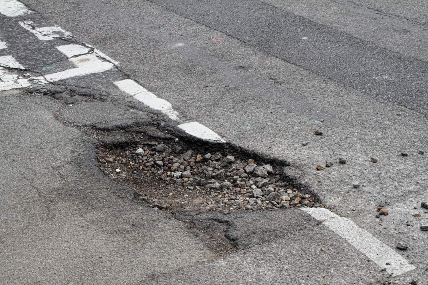 Bad repair pothole in road T-junction suffers frost damage 