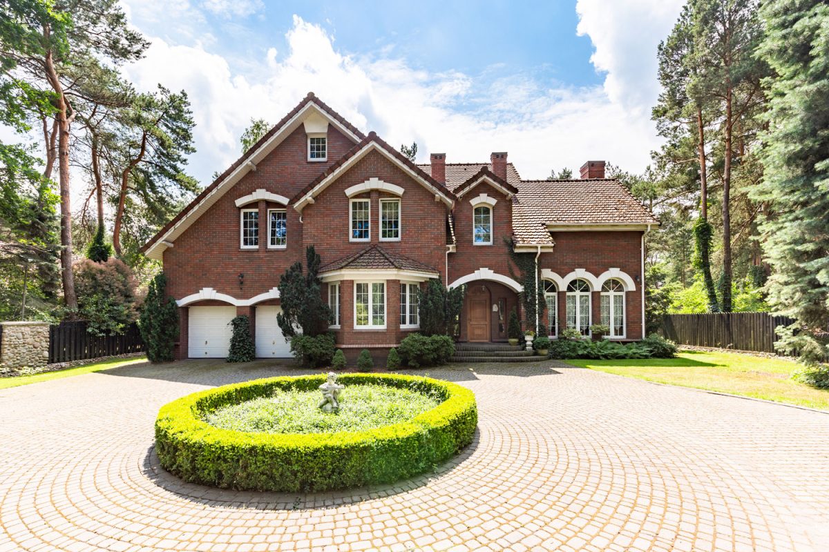 Brick walled mansion with matching white trims and window frames and a brick driveway roundabout