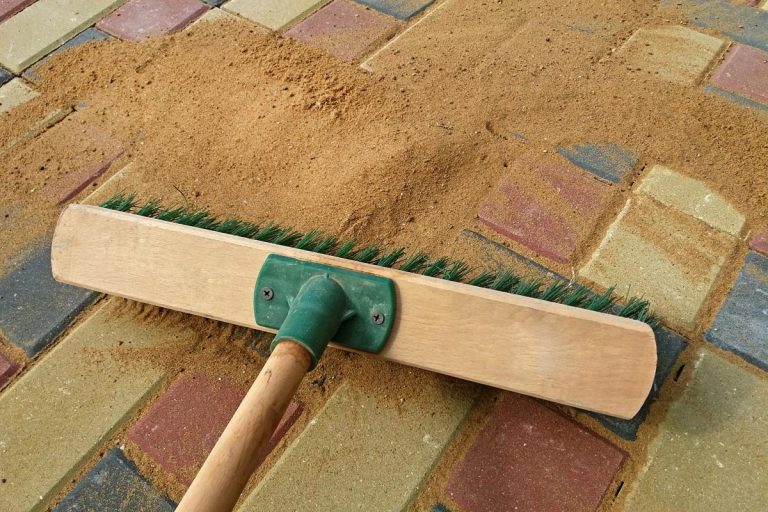 Brushing a polymeric sand to fill paving joints, Does Polymeric Sand Prevent Weeds? [Plus Helpful Tips To Stop Weed Growth In Pavers!]