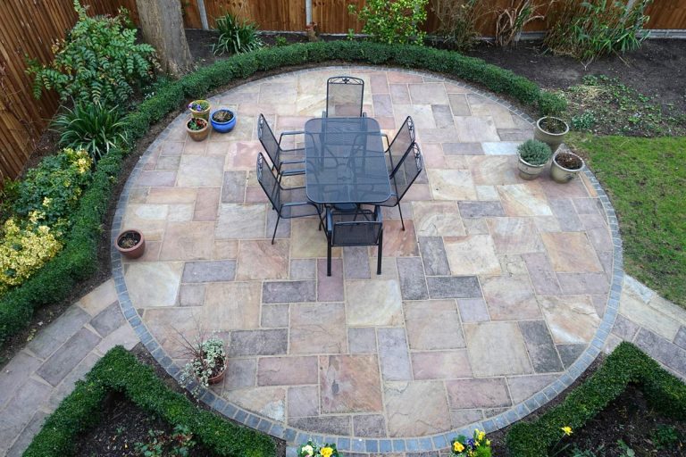 A circular garden patio with table and chairs, How Long Do Unilock Pavers Last? [Incld Do They Fade]