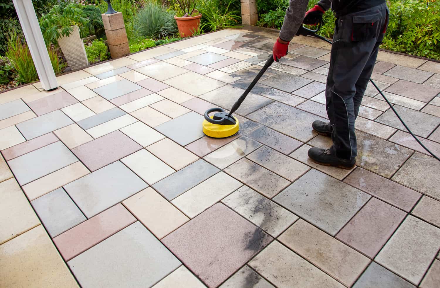 Cleaning stone slabs on patio with the high-pressure cleaner.