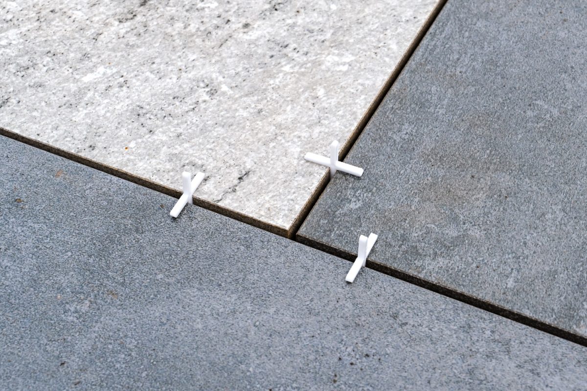 Close up of plastic spacers being used to keep a consistent gap between porcelain slabs being laid for a patio