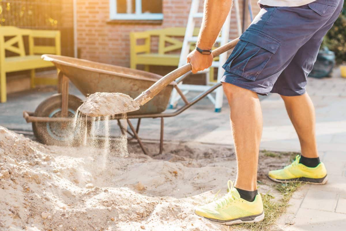 Cropped image of man digging sand with a shovel - DIY do it yourself and home works concept


