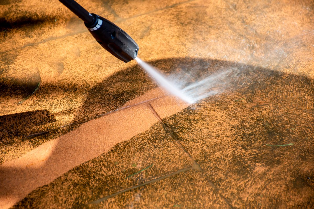 Defocused image. Cleaning backyard paving tiles pathway with high pressure washer. Spring clean up

