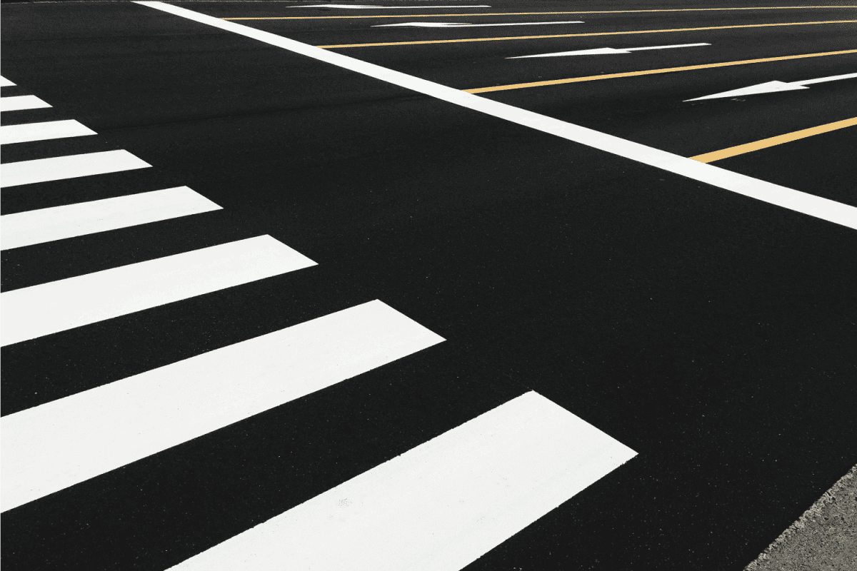 Full frame shot of zebra crossing sign or crosswalk on black asphalt road