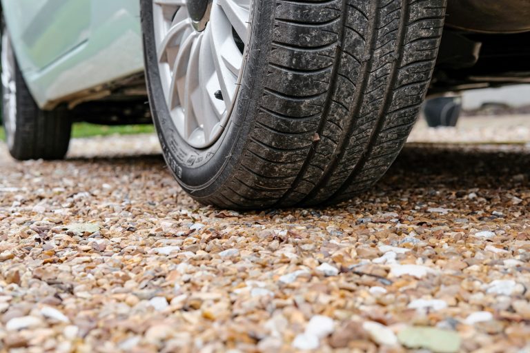 Ground level view of a new car, showing the rear tyre and tread together with the alloy wheel - Is Crushed Concrete Better Than A Gravel Driveway [Pros & Cons Of Recycled Concrete]