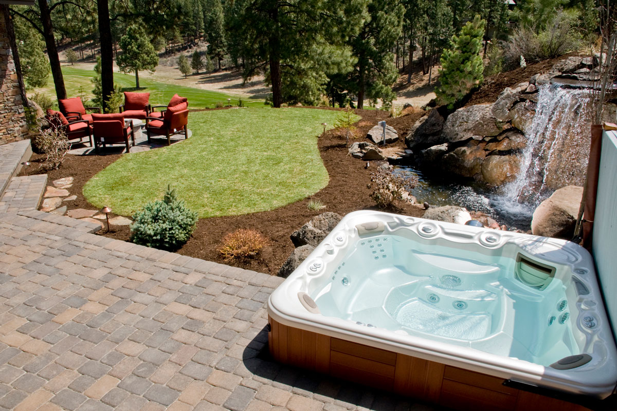 Hot tub in a beautiful landscape with pavers, Can A Hot Tub Sit On Pavers? [And How Thick Should They Be To Support It?]