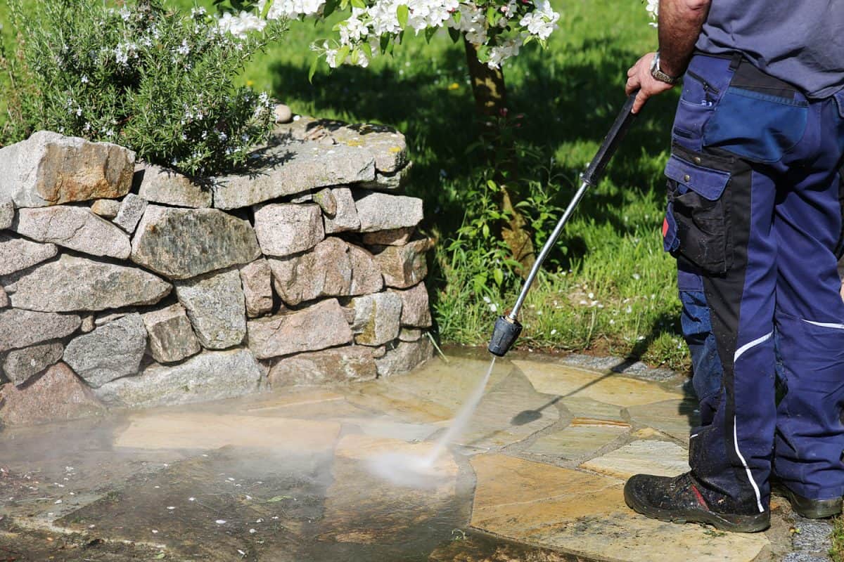 Janitorial service, cleaning of stones in the garden with the high-pressure cleaner.
