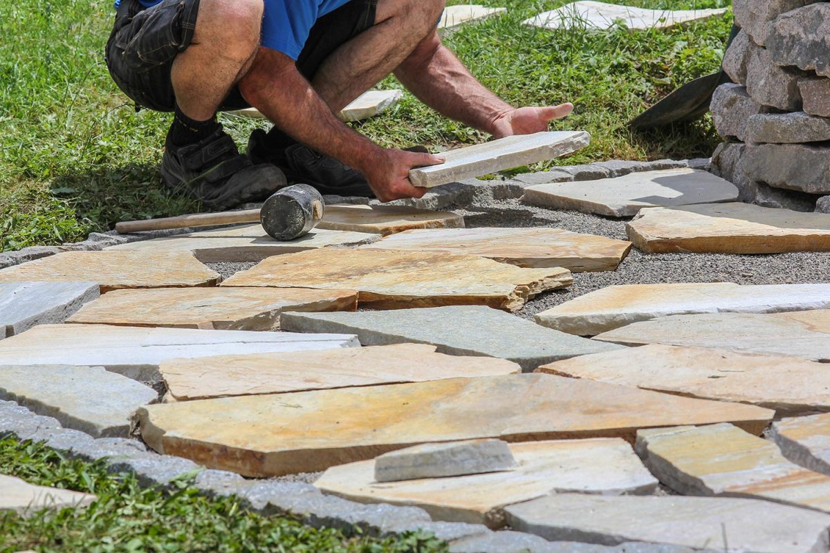 Man installing marble plates pavers in the garden