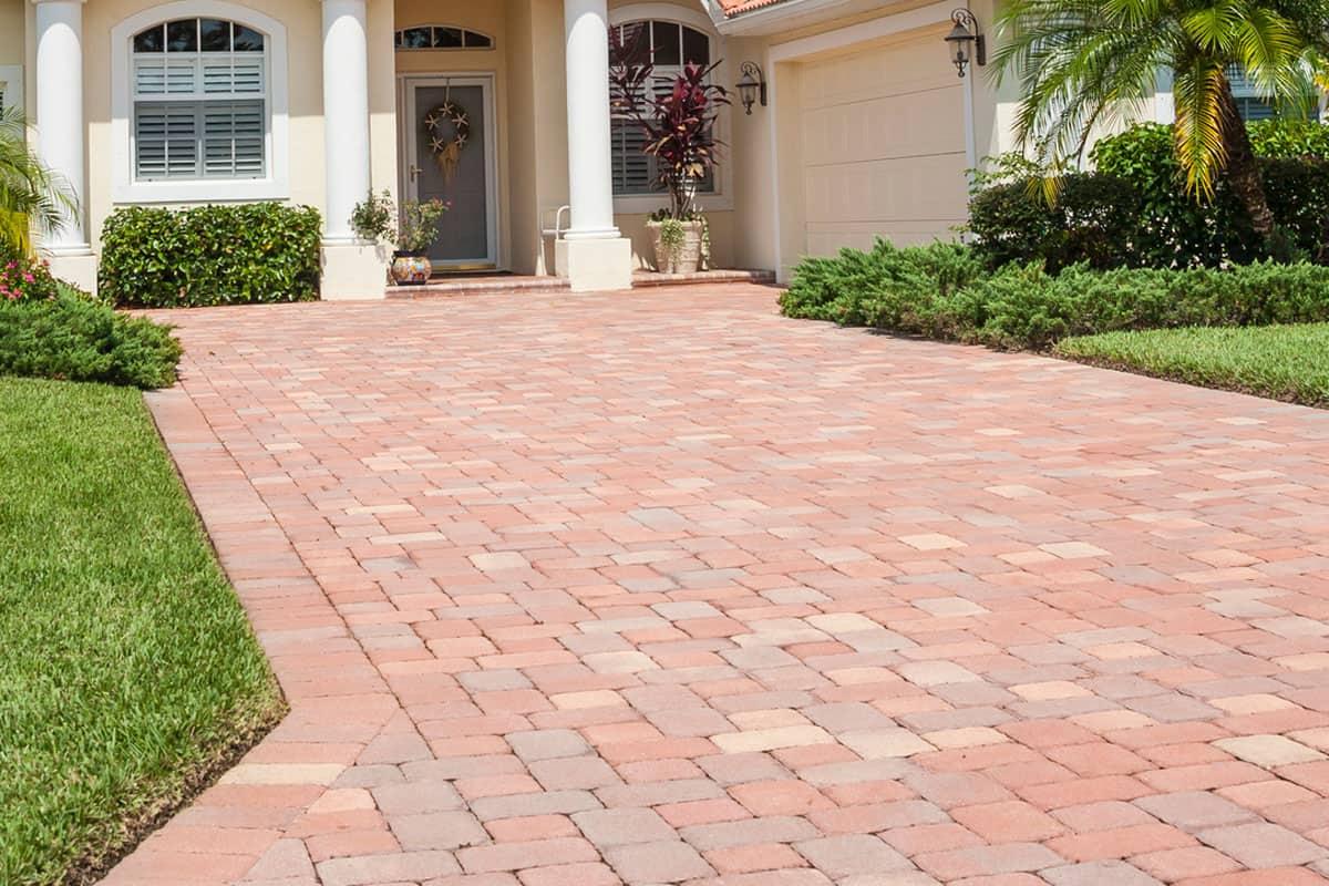 New contemporary home with driveway, front lawn and lush tropical foliage, Do Pavers Shift Over Time? [And How To Prevent And Repair]
