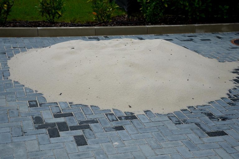 A pile of silica sand used as a material for backfilling the joints between the tiles of concrete gray interlocking paving on the construction site, Types Of Paver Joint Sand [Considering The Pros & Cons Of Each]