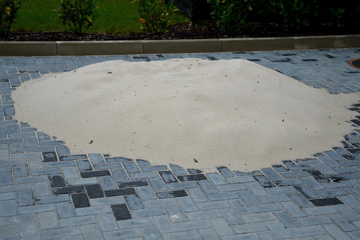 A pile of silica sand used as a material for backfilling the joints between the tiles of concrete gray interlocking paving on the construction site