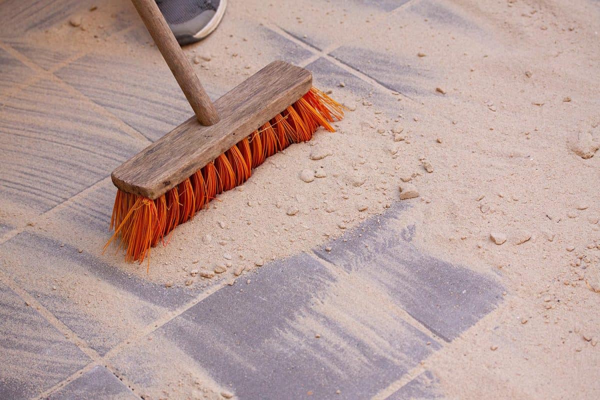 Sand spread over the surface of pavers or tiles and sweeping it into the spaces with a broom