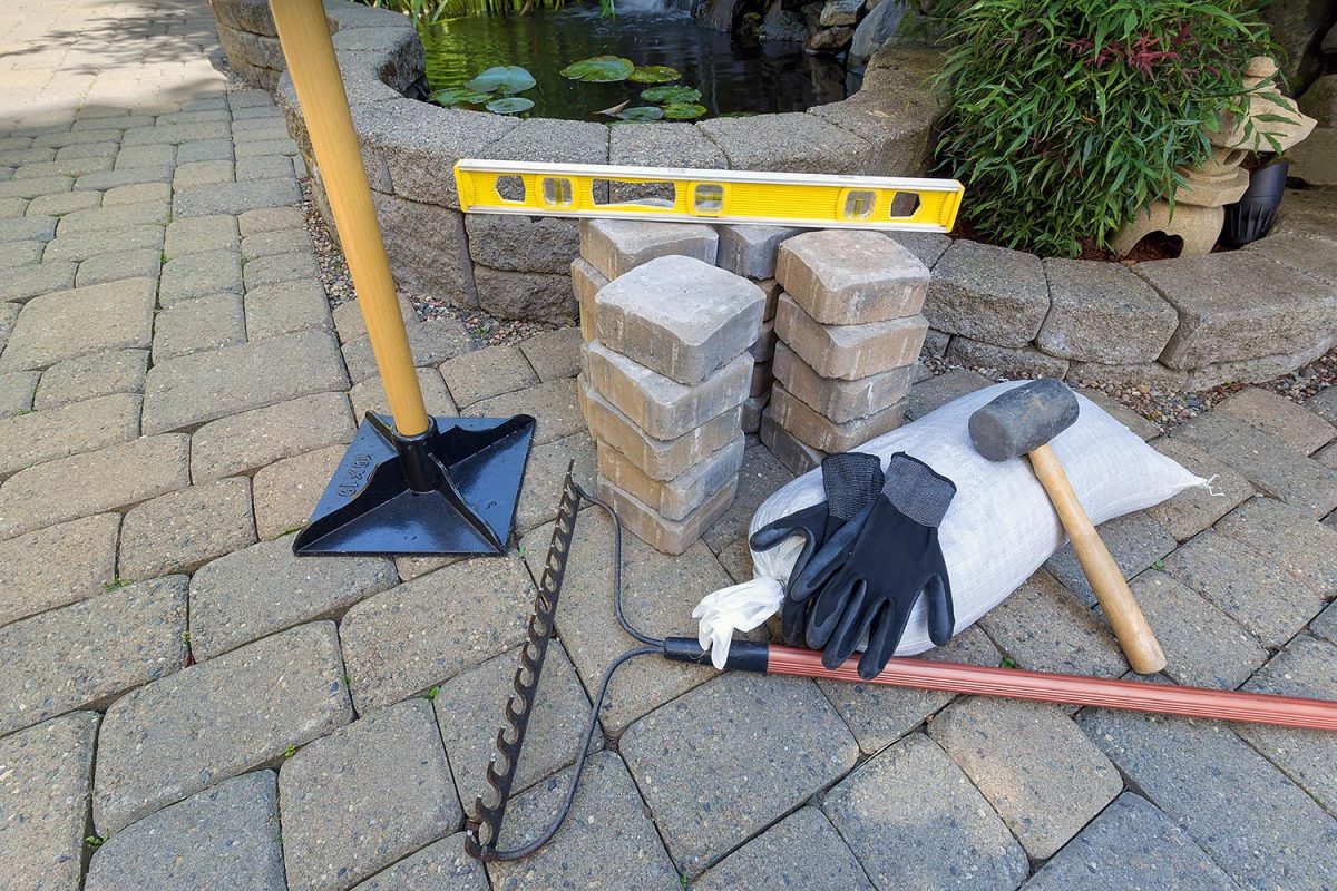 Stone Pavers for backyard patio pond hardscape with garden landscaping tools gloves level rubber mallet sand gravel tamper