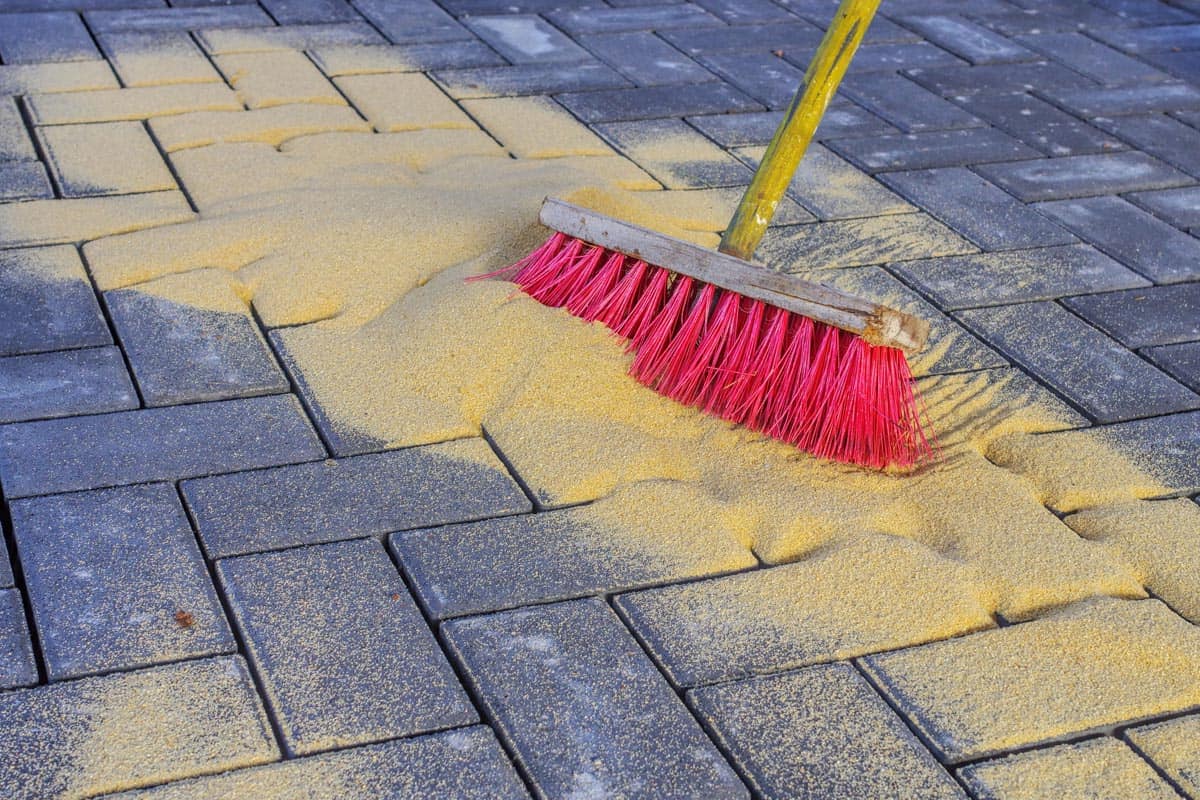 Sweeping in a joint sand on a construction site, Is Polymeric Sand Permeable? [What You Should Know Before Filling Paver Joints]