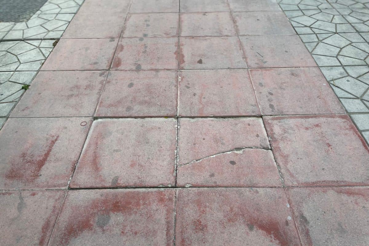 The pavement along the road is made of concrete with cracks around it.

