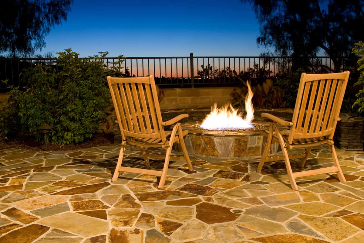 Twilight view of a back yard with fire pit and flagstone paver, Can Flagstone Be Stained? [And How]