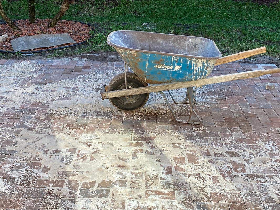Wheeling in sand to fill cracks on new brick paver patio