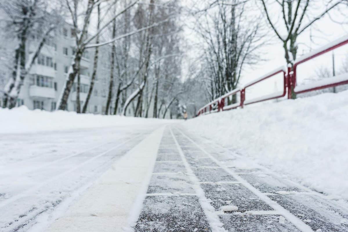 Winter frozen pavement walkway under snow in a park