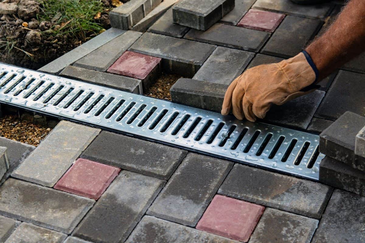 Worker placing brick pavers near the drainage