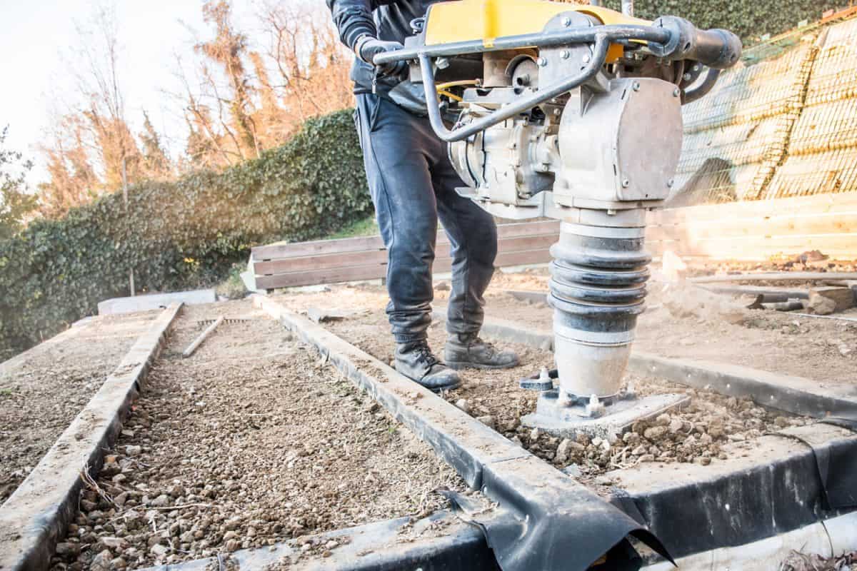 Worker using a tamper for the patio pavement