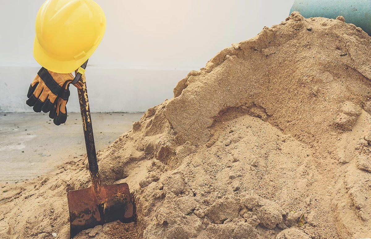 Желтые шлемы, перчатки и лопаткоулавливатель на куче песка
