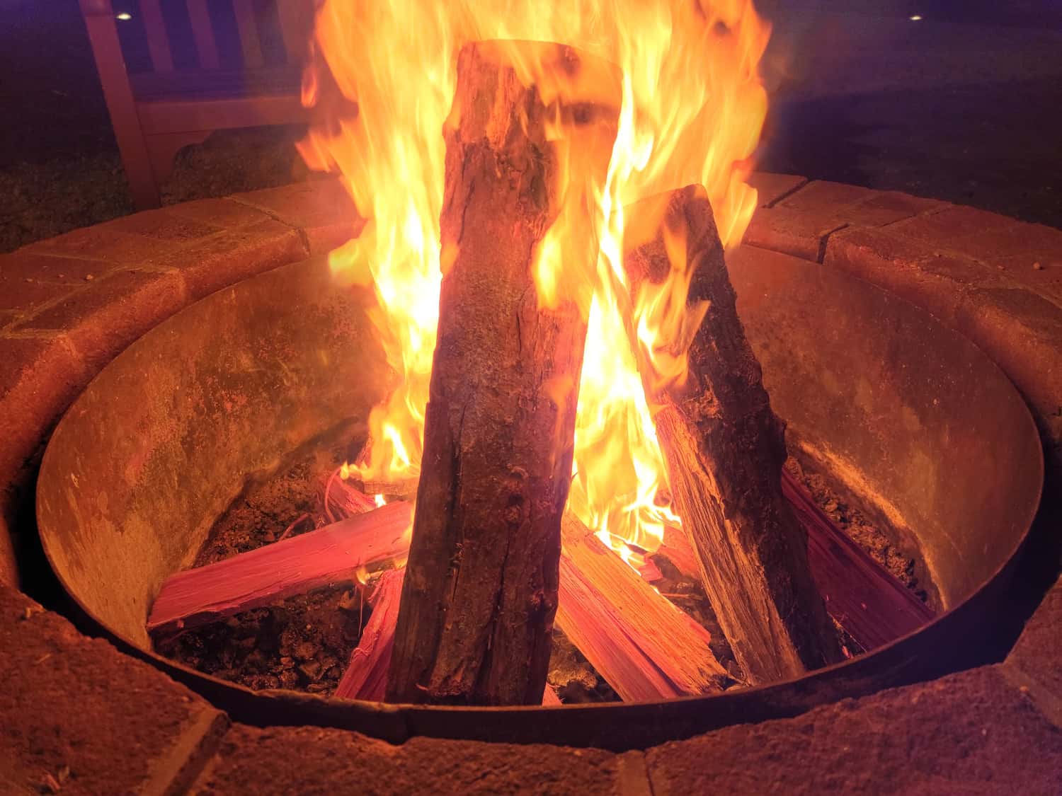logs or wood on fire in fire pit with flames and smoke