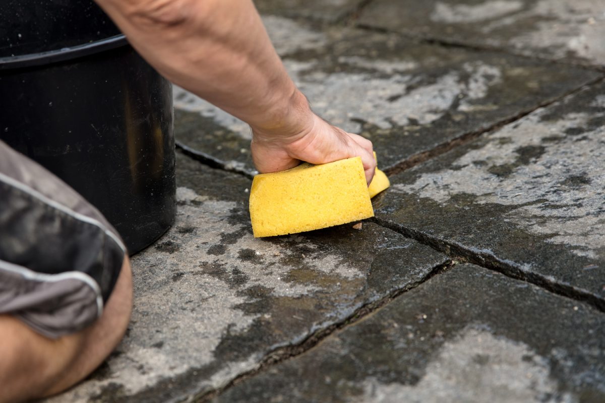 man is washing fresh mortar joints with a sponge

