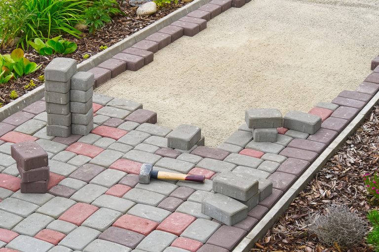 worker laying paving stones. stone pavement, construction worker laying cobblestone rocks on sand, Polymeric Sand Vs Regular Sand: Which Is Best For Pavers?