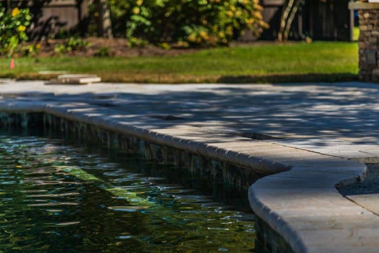 A pool and a travertine patio under construction in a backyard, Can You Grout Travertine Pavers?